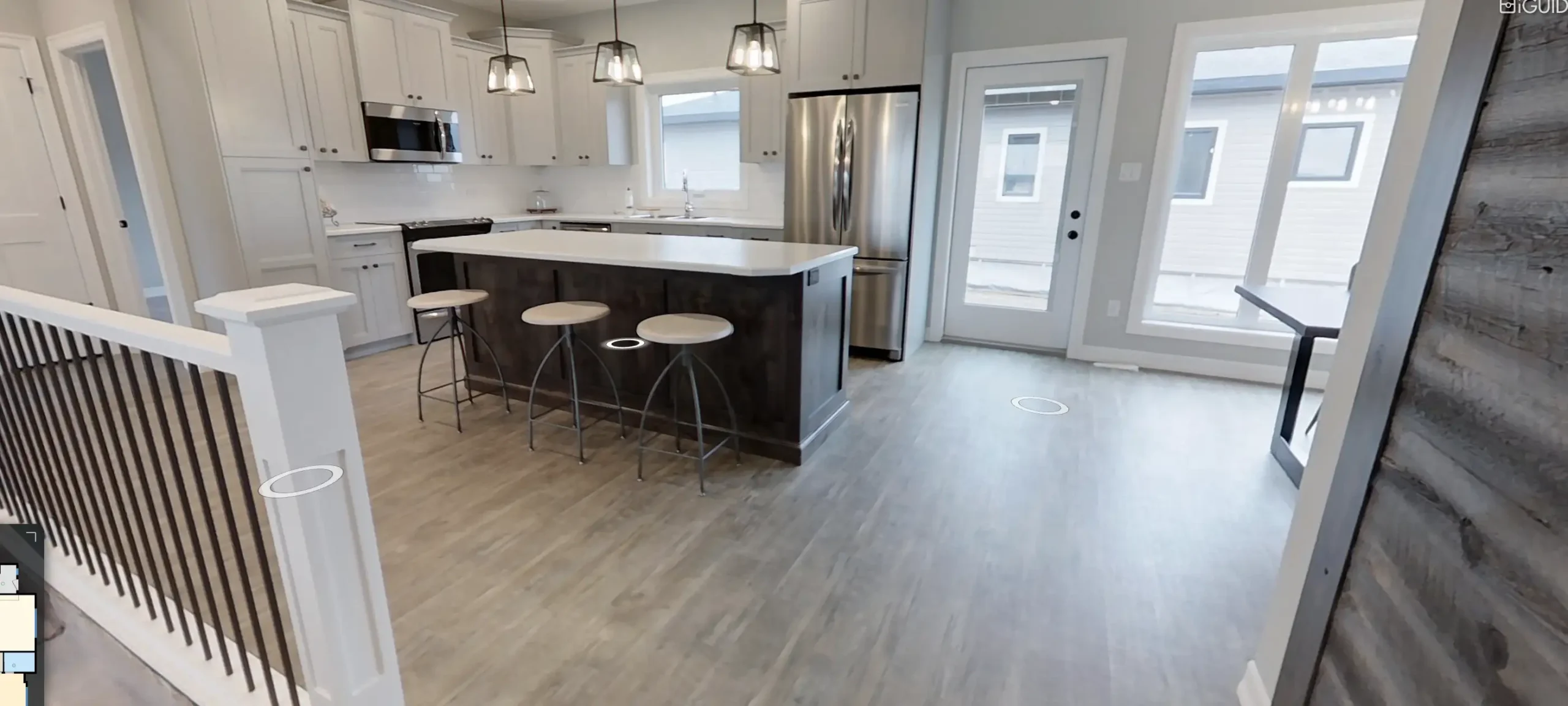 RTM home kitchen in Alberta or Saskatchewan with white shaker cabinets, large island with three stools, pendant lights, stainless steel appliances, and a patio door.